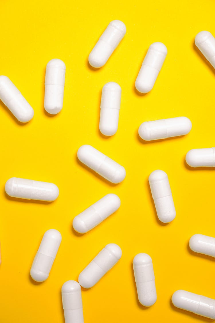 White Medication Capsules On Yellow Surface