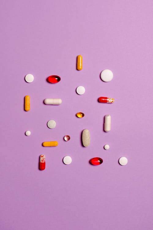 Free Medication Pills Isolated on Purple Background Stock Photo