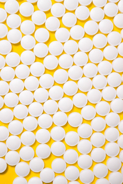 White Medication Pills Isolated on Yellow background