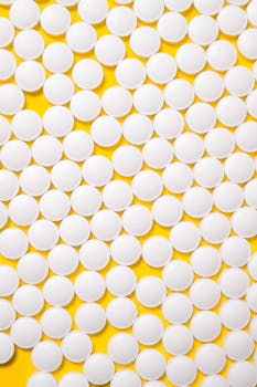 白色圆形药丸在鲜艳的黄色背景上展示了制药主题
