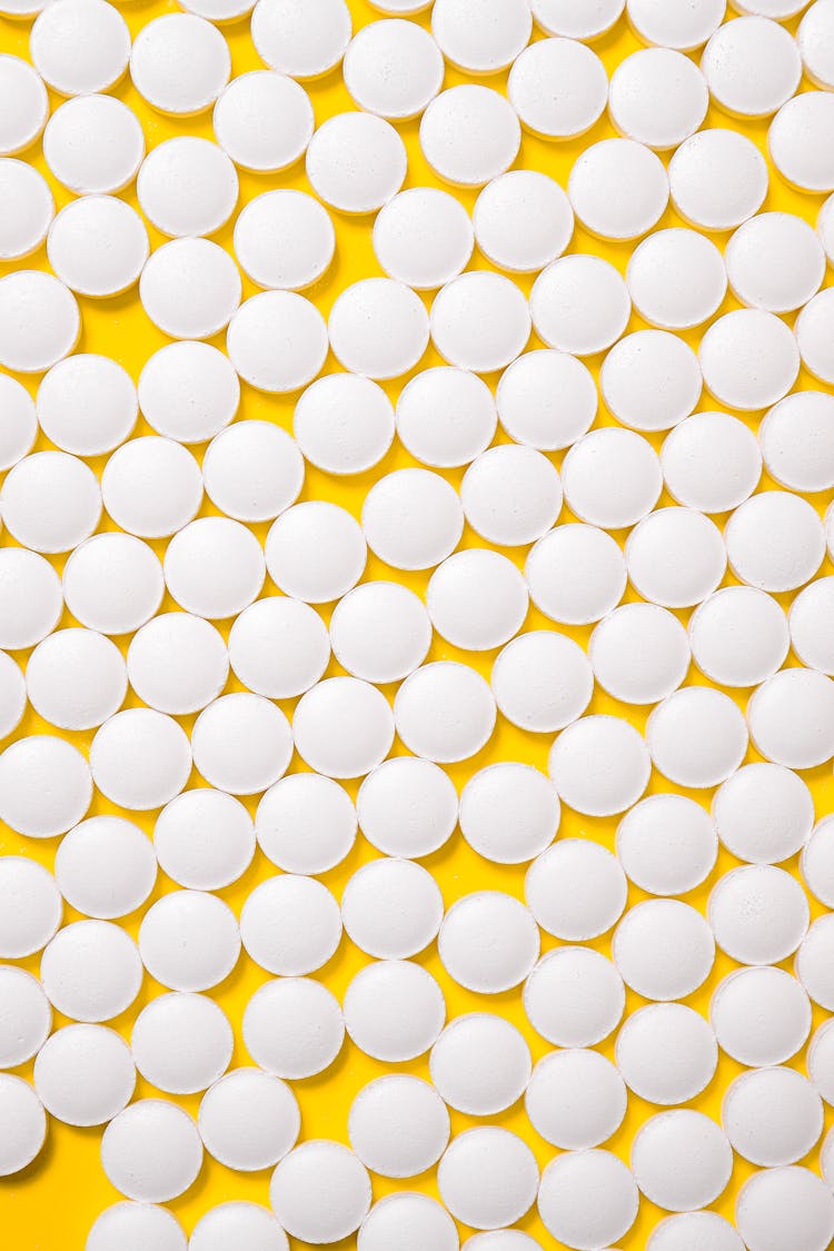 White Medication Pills Isolated On Yellow Background