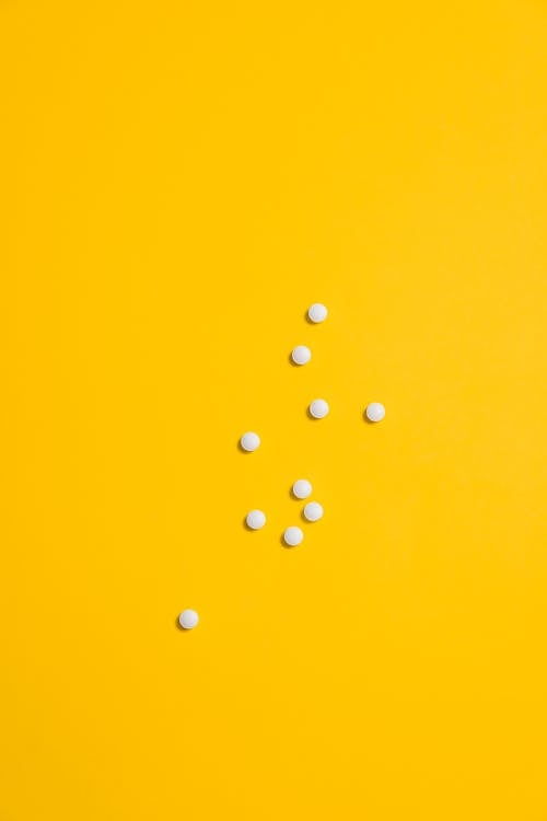 White Medication Pills Isolated on Yellow background