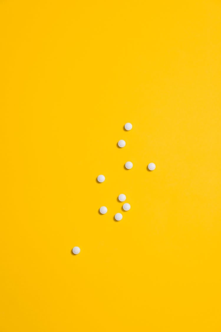 White Medication Pills Isolated On Yellow Background