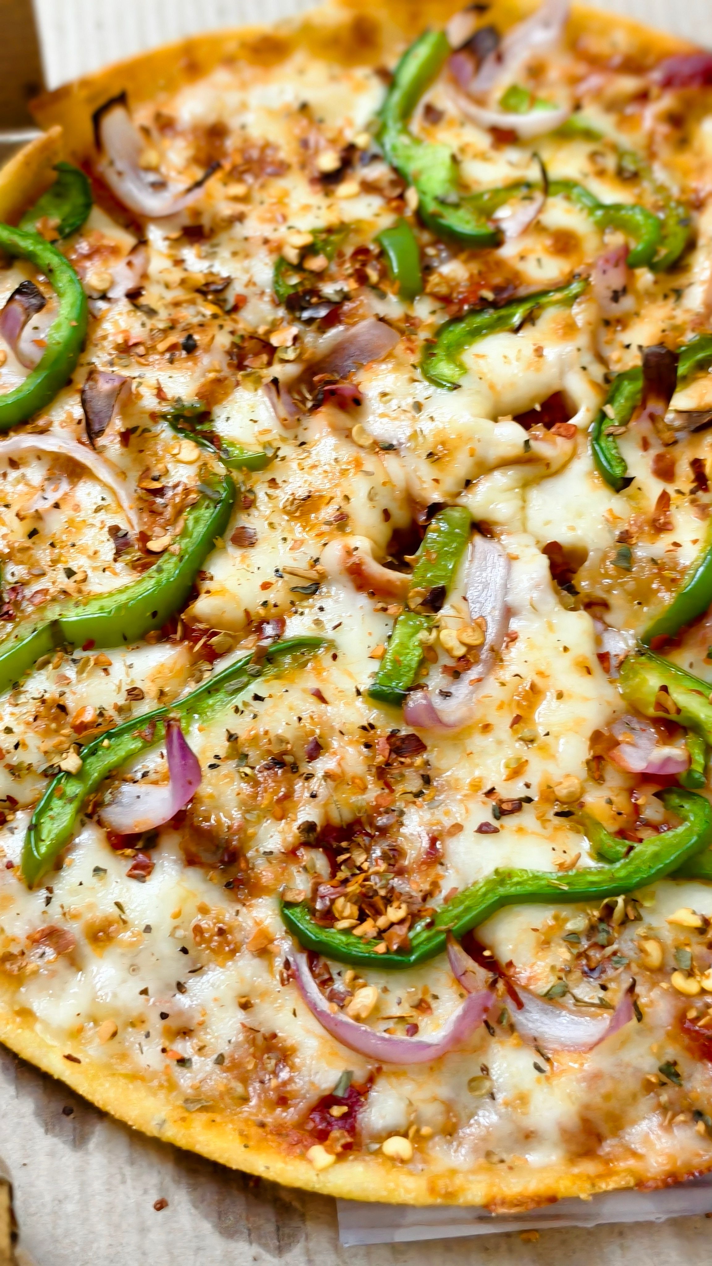 Close-up of a cheesy vegetarian pizza topped with green peppers and onions, perfect for food lovers.