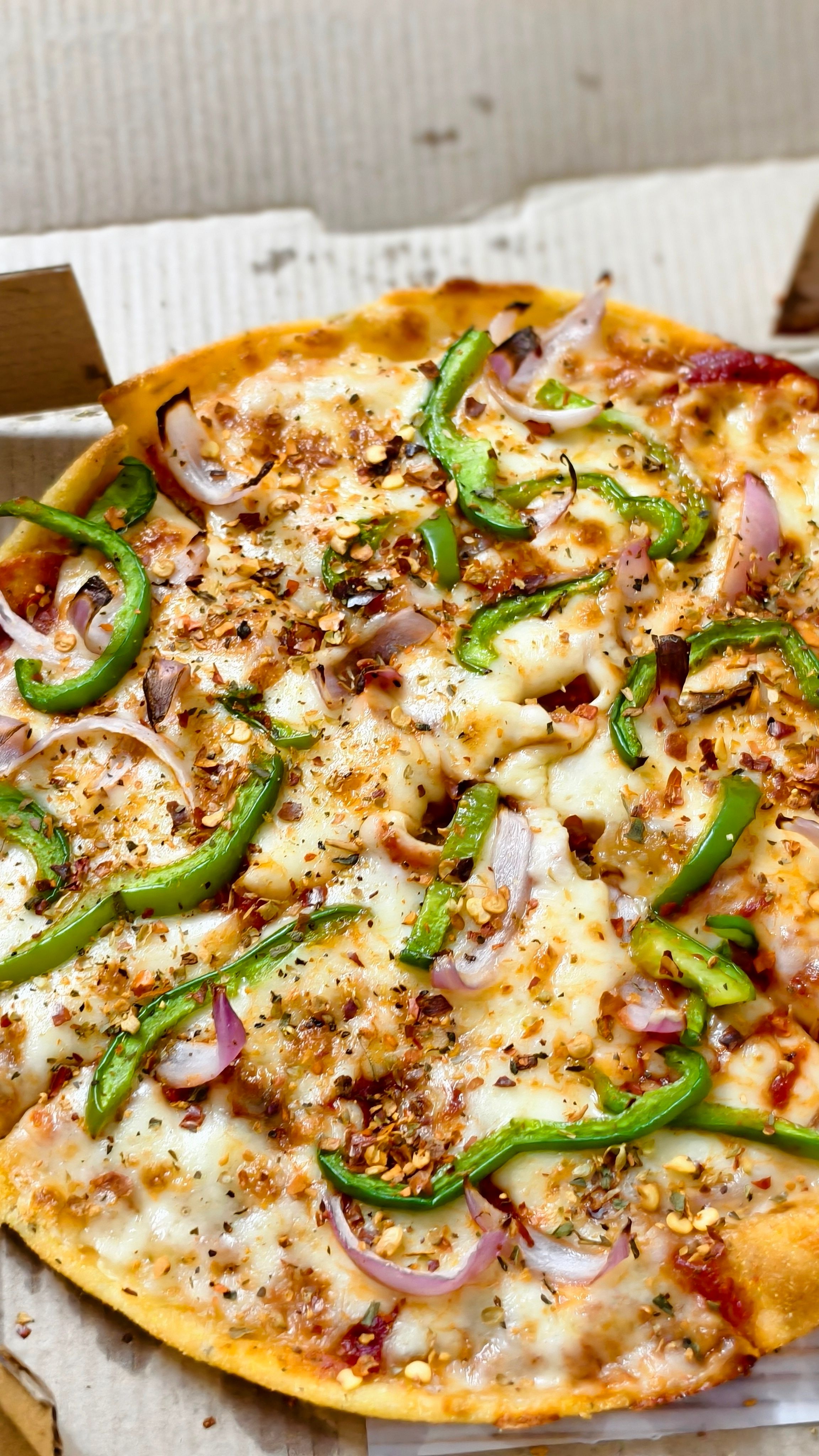 Close-up of a freshly baked cheese pizza with green pepper and onion toppings.