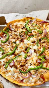 Close-up of a freshly baked cheese pizza with green pepper and onion toppings.