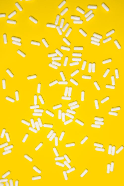Free White pills Isolated on Yellow background Stock Photo