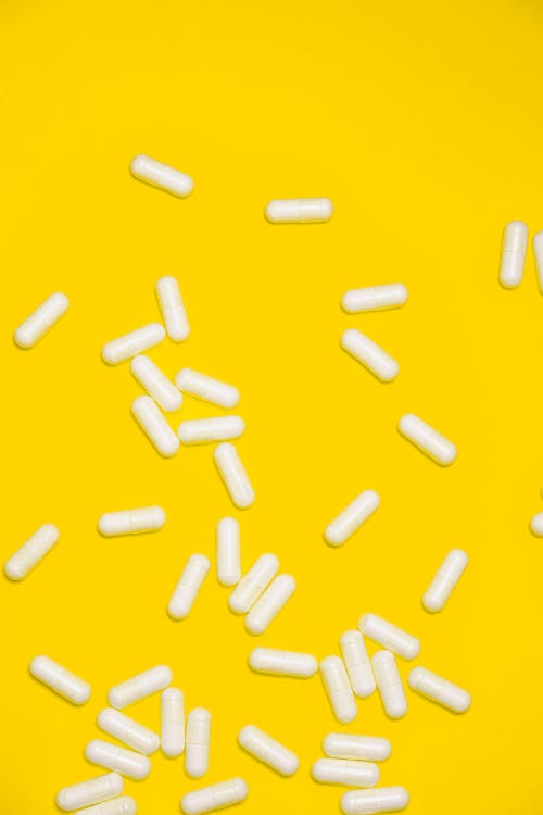 黄色の背景に分離された白い薬の丸薬
