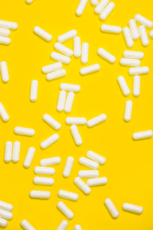 Free White Medication Pills Isolated on Yellow background Stock Photo