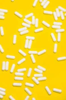 大胆的黄色背景上，散布着一系列白色胶囊，象征着医疗保健