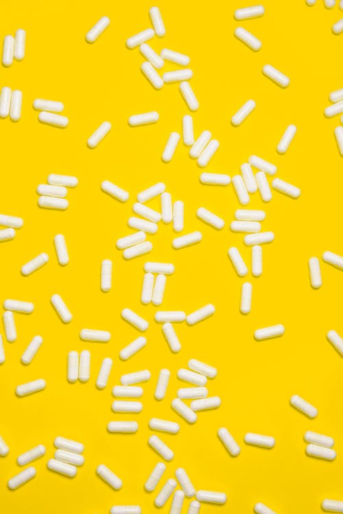 Free White pills Isolated on Yellow background Stock Photo