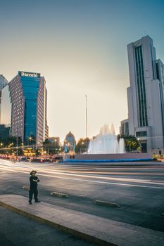 Long exposure shot of traffic near iconic fountain in Ciudad de México at twilight.