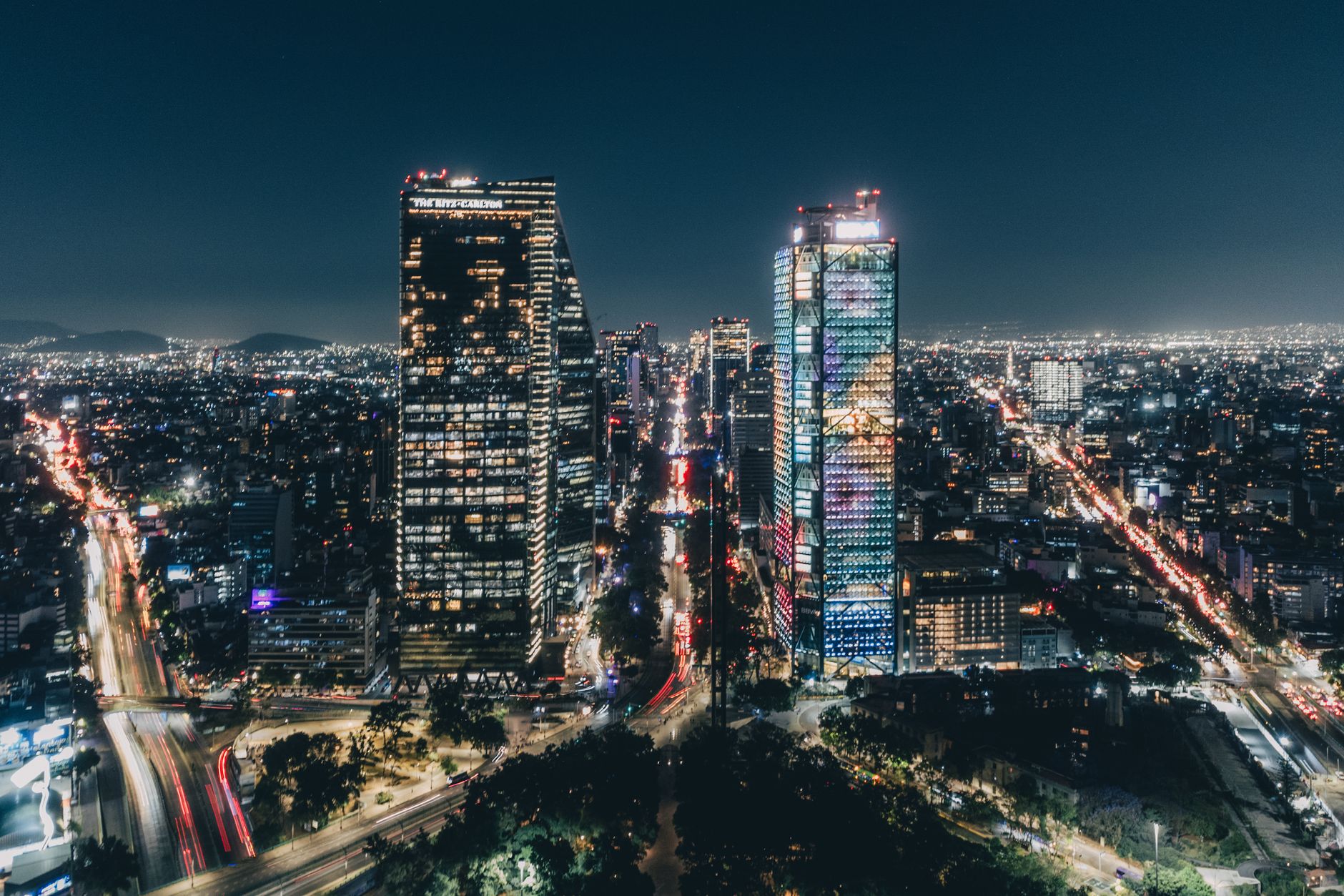 The Mexico City skyline at night with lit towers along a broad avenue