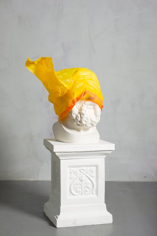 Patung Tertutup Plastik Kuning Di Latar Belakang Putih
