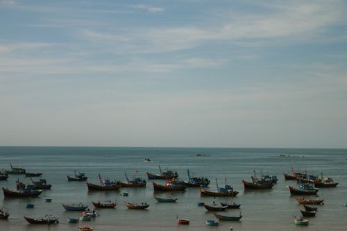 Free A serene view of traditional fishing boats on a calm sea in Vietnam under blue skies. Stock Photo