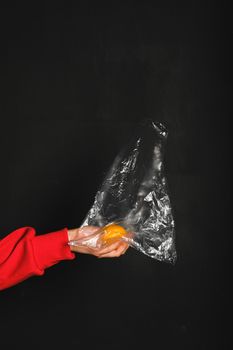 塑料袋里装着橙子，背景是深色的，突出了塑料垃圾