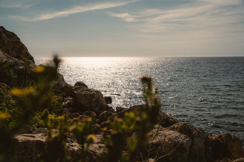 Free Tranquil seaside view with sunlit ocean and rocky shoreline in Malta. Stock Photo