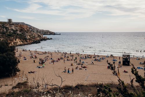 Free Overhead view of Golden Bay Beach in Malta with people enjoying a summer day by the seaside. Stock Photo