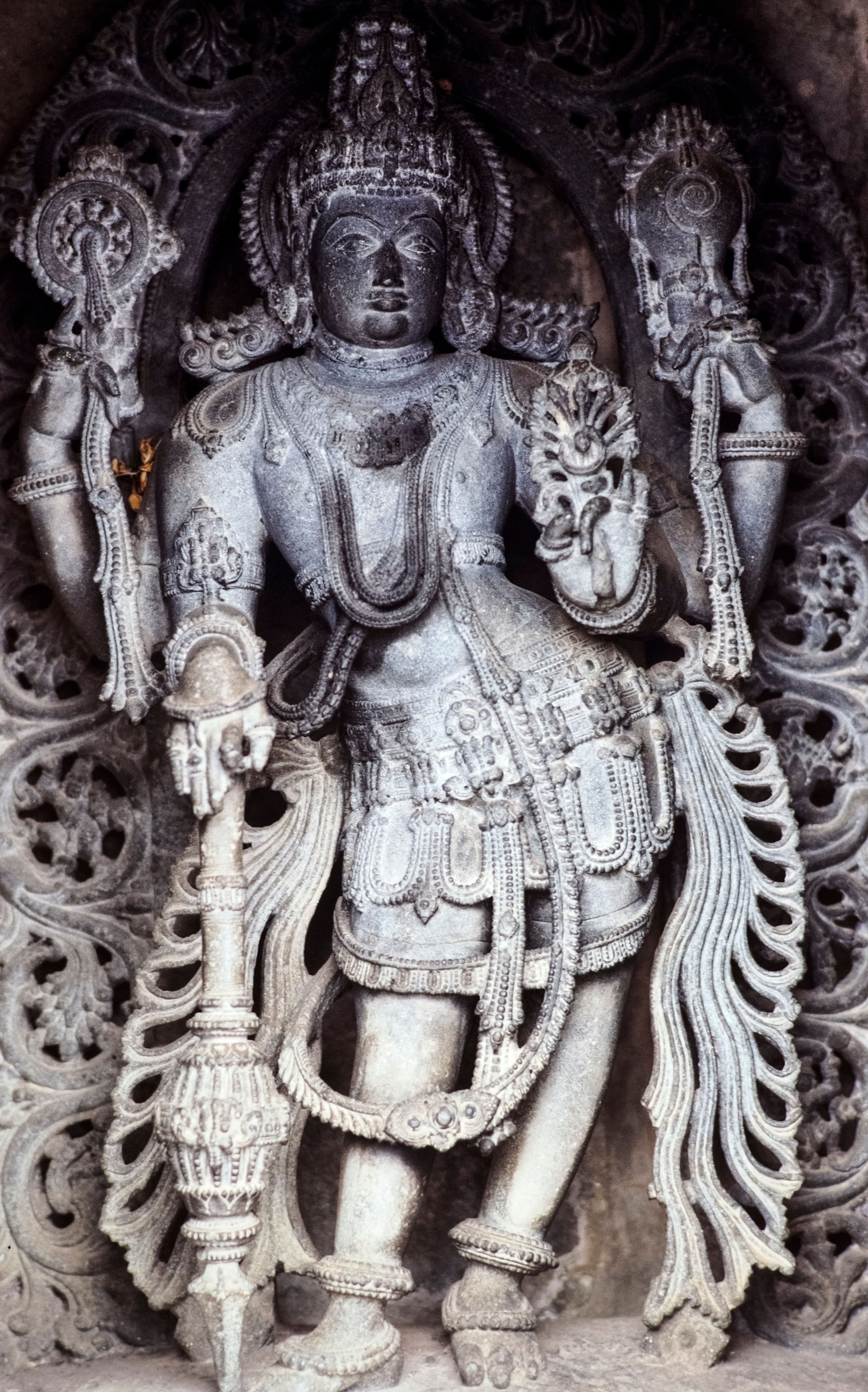 Close-up of an ornate stone sculpture depicting a Hindu deity with intricate carvings, India.
