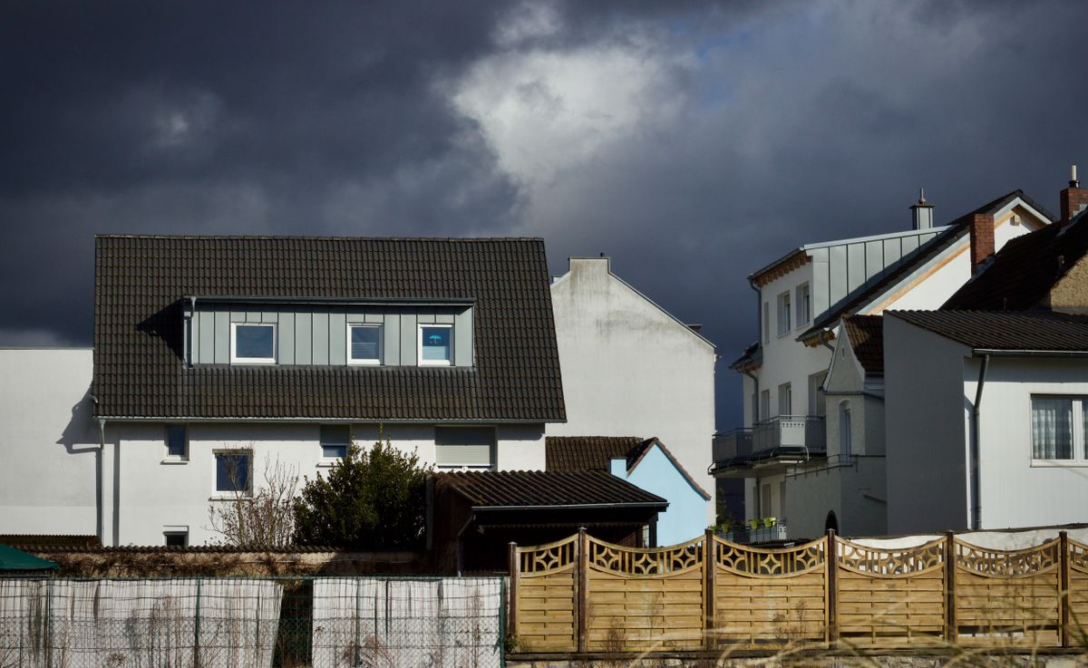 Wohnhäuser mit Dachgauben unter dunklen Sturmwolken, Thema Stabilität von Fliegengittern bei Sturm