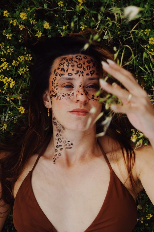 Free Captivating portrait of a woman with leopard face paint, surrounded by flora in Bodrum, Türkiye. Stock Photo