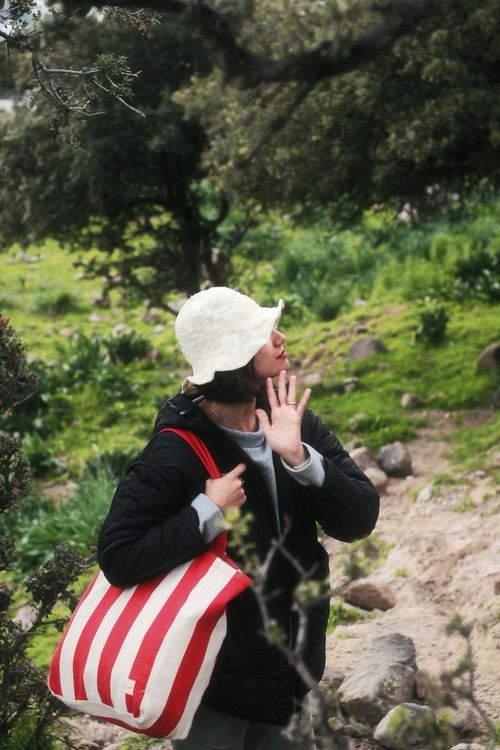 Free A woman explores the lush, green terrain of Bodrum, Türkiye, with a red and white bag, embracing nature. Stock Photo