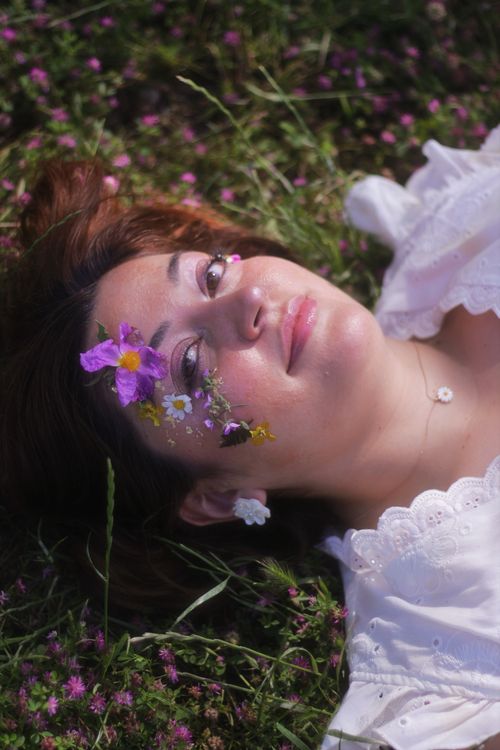 Free A peaceful portrait of a woman lying on grass adorned with flowers in Bodrum, Türkiye. Stock Photo