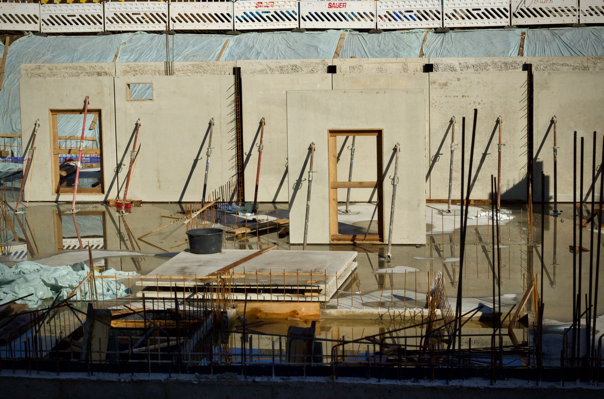 Construction site featuring concrete walls with window and door frames under daylight.