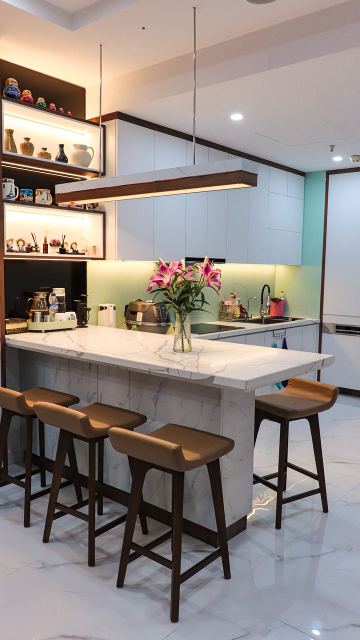 A kitchen under-cabinet coffee bar storage shelf with mugs and barista tools hanging below upper cabinets