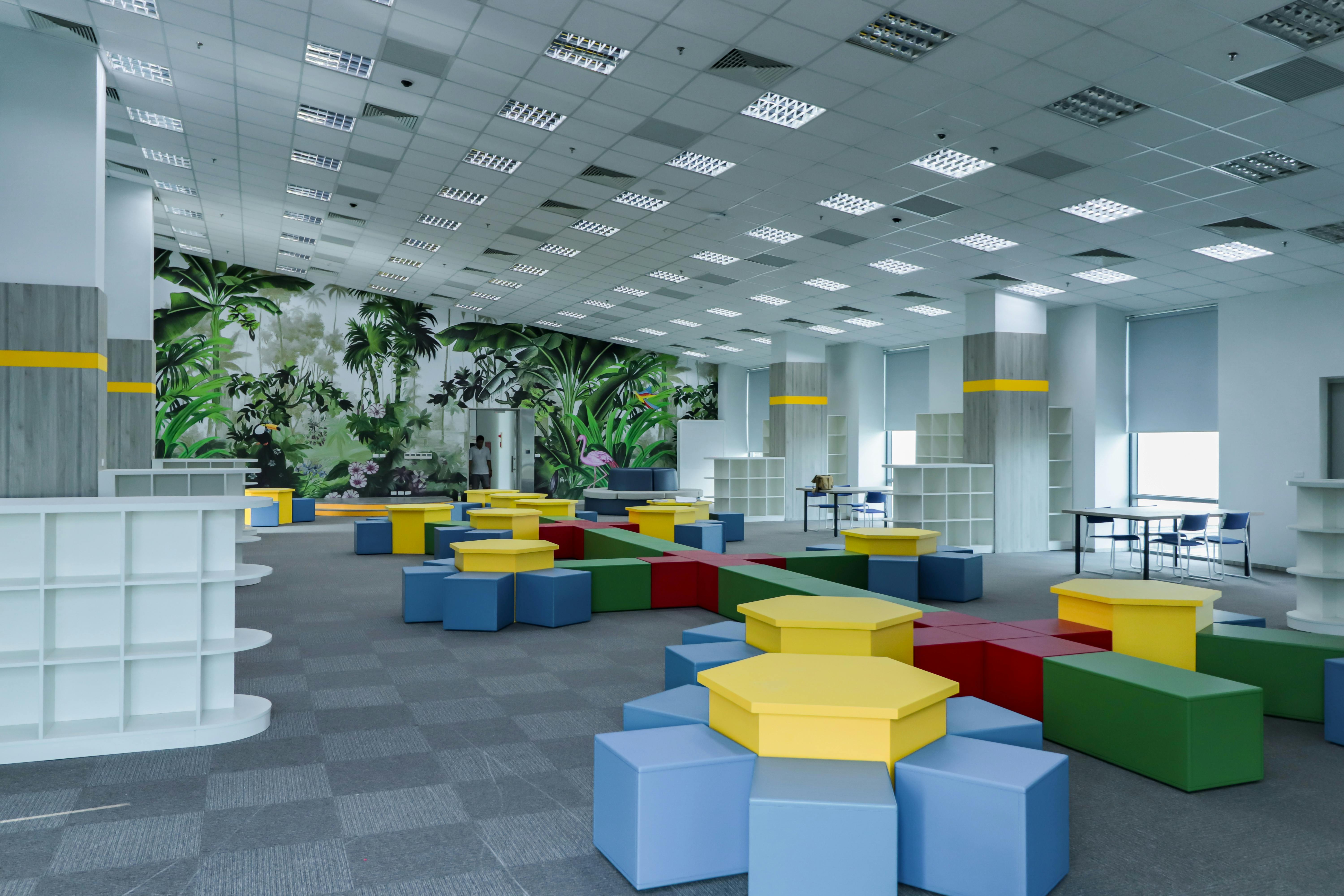 Vibrant indoor playground with colorful geometric seating and jungle-themed walls.