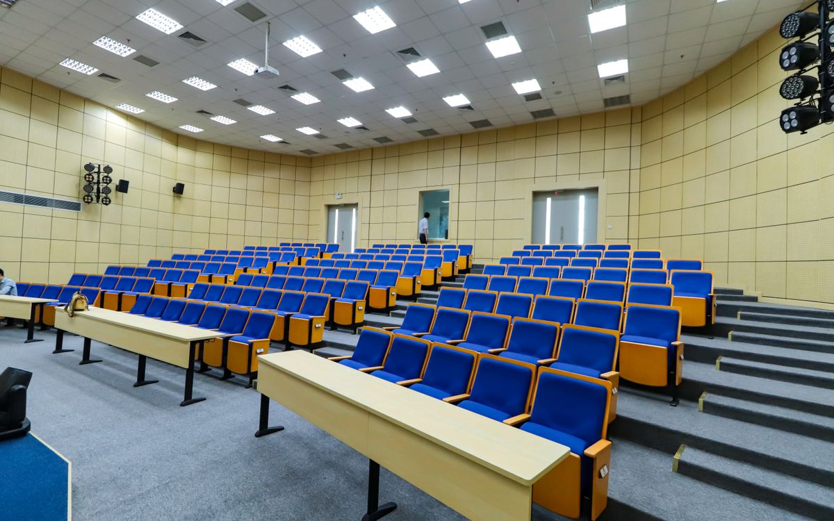 Spacious lecture hall with blue seats and desks ready for students.