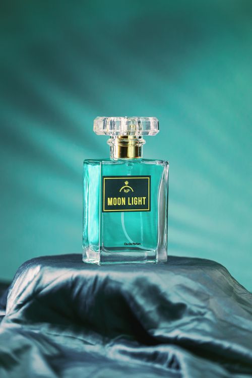 Free Artistic shot of Moon Light perfume bottle set against a soft blue backdrop. Perfect for luxury branding. Stock Photo