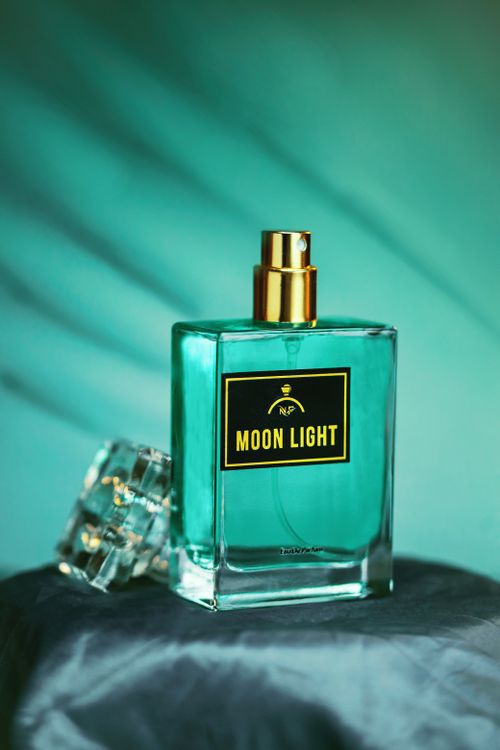 Free Artistic capture of a Moon Light perfume bottle with moody lighting and soft blue tones. Stock Photo