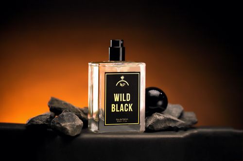 Free Luxurious Wild Black perfume bottle with bold, dramatic lighting on rock stones. Stock Photo
