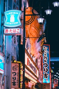 Dynamic Tokyo street at night, illuminated by colorful neon signs and bustling city life.