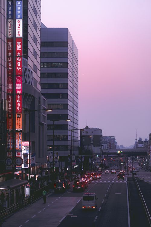 Free Urban street scene at twilight with skyscrapers and traffic under a pink sky. Ideal for cityscape themes. Stock Photo