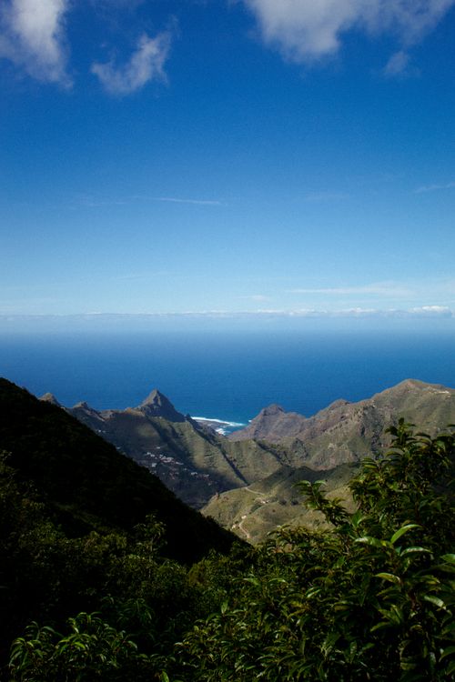 Free Stunning aerial view of Tenerife's mountainous landscape meeting the vast Atlantic Ocean under a clear blue sky. Stock Photo