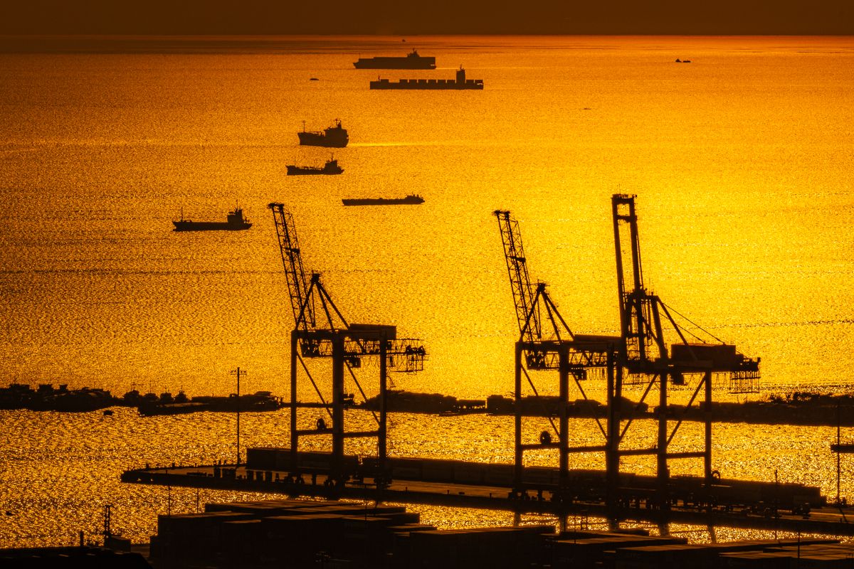 Cargo ships berthed at an industrial harbor during golden hour
