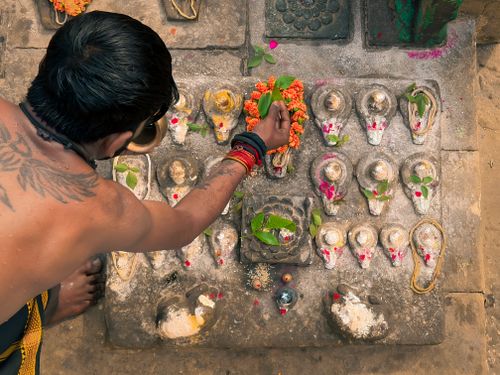 Free A man performing a traditional Hindu ritual with offerings on a stone platform in Varanasi, India. Stock Photo