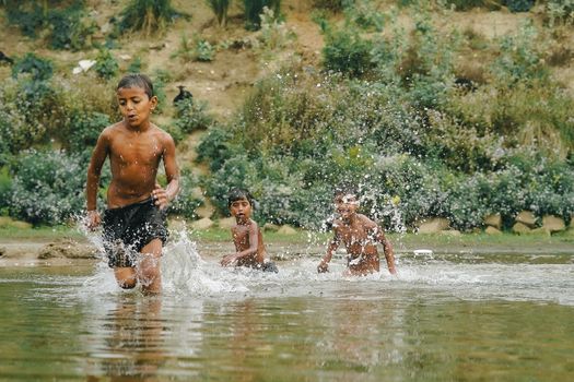 Kids enjoying summertime splash in a river, creating vibrant water sprays.