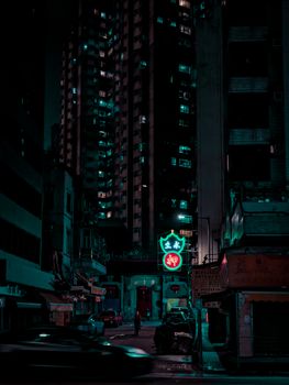 Moody nighttime scene of Kowloon, Hong Kong with neon lights and high-rise buildings.