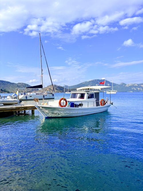 Free White boat docked in the calm waters of Kastellorizo, Greece, under a clear blue sky. Stock Photo