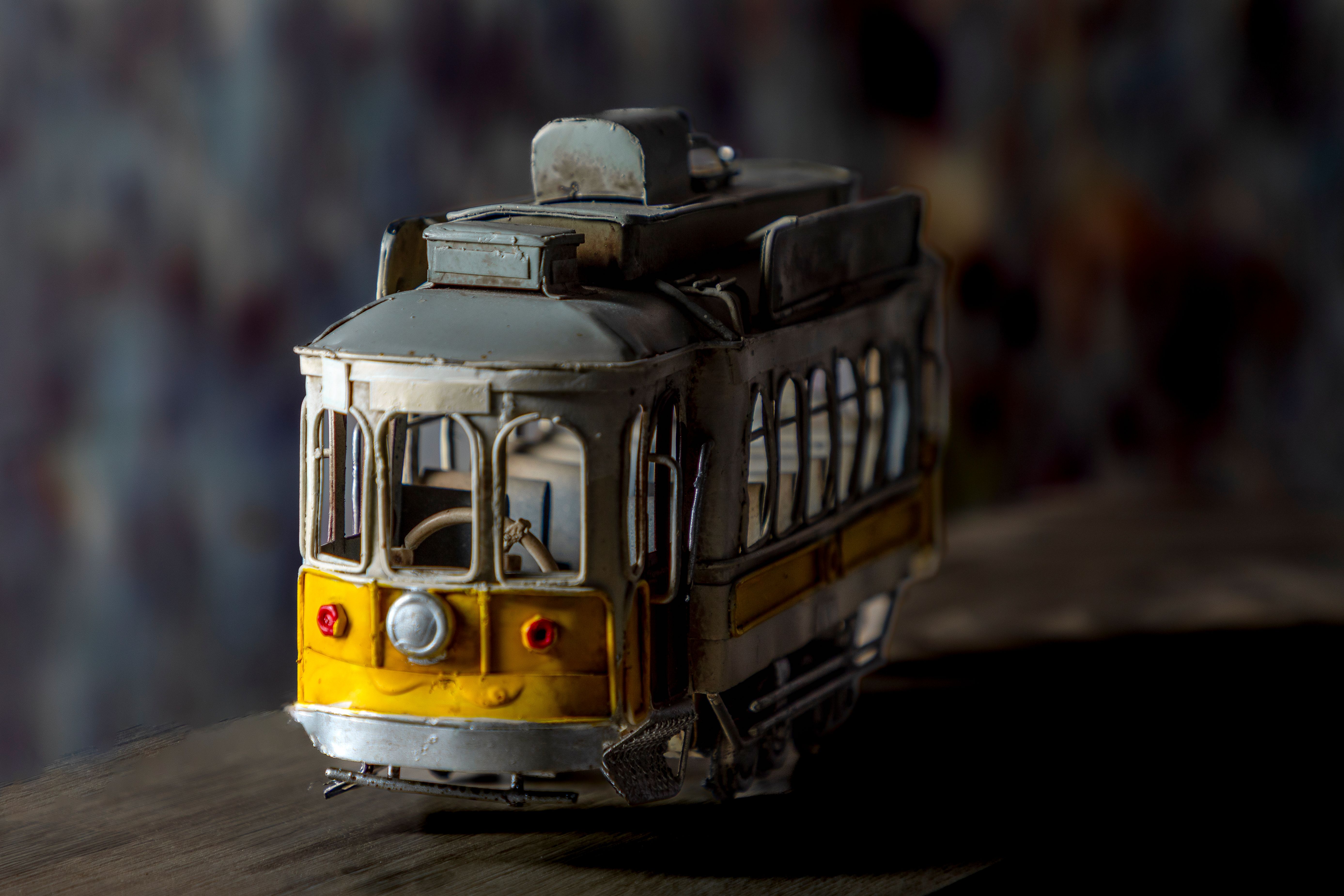 Close-up of a vintage metal tram model on a wooden surface, showcasing its intricate design.