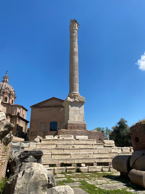 Free A single ancient Roman column stands tall beneath a clear blue sky in the ruins of Rome. Stock Photo