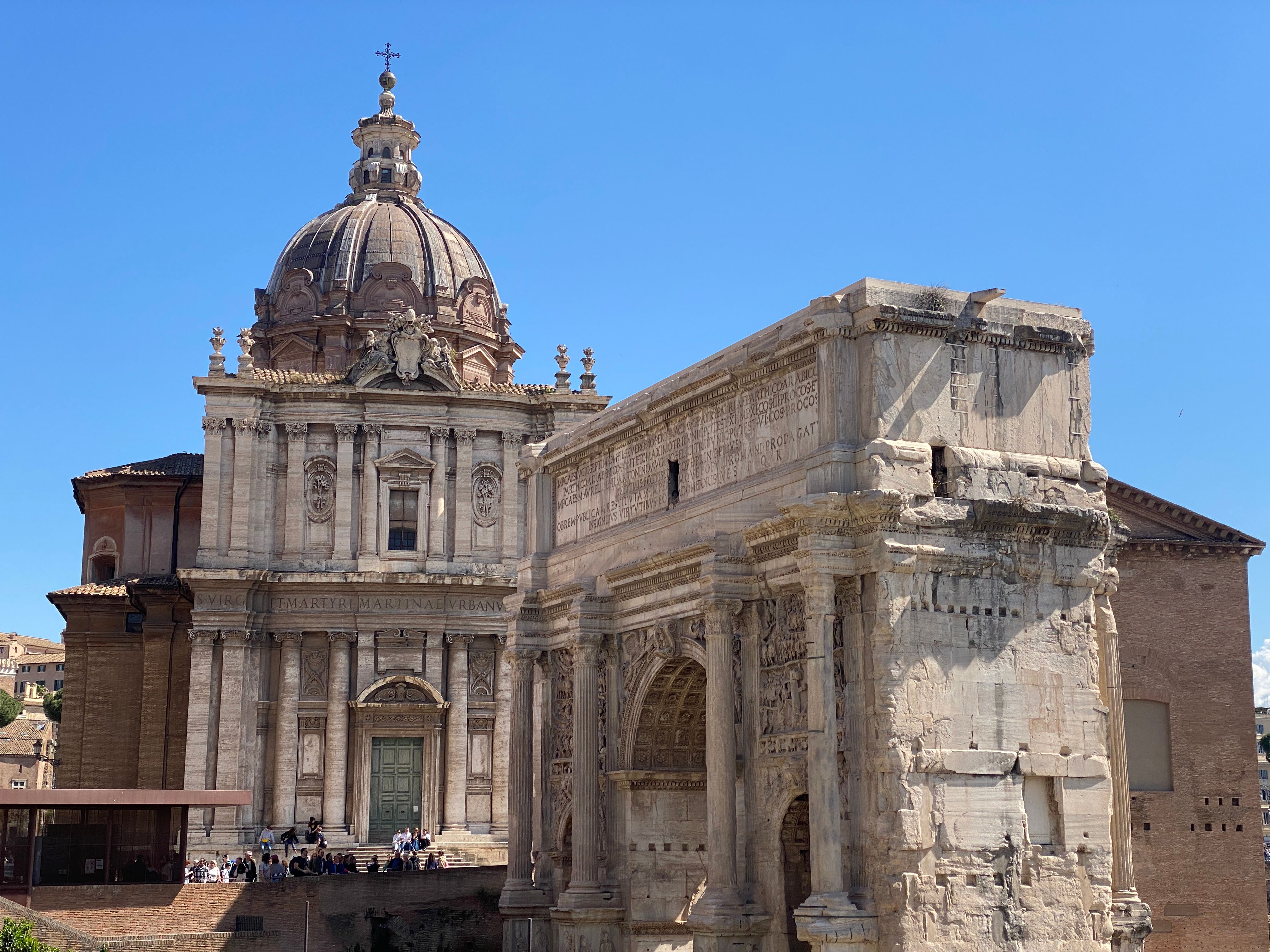 View of the historic Arch of Septimius Severus and nearby church in Rome.