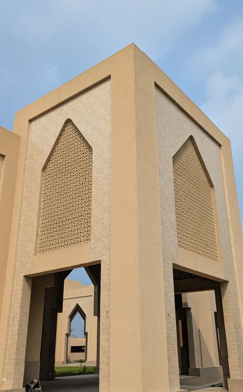Free Contemporary beige structure featuring Islamic architectural details against a clear sky. Stock Photo