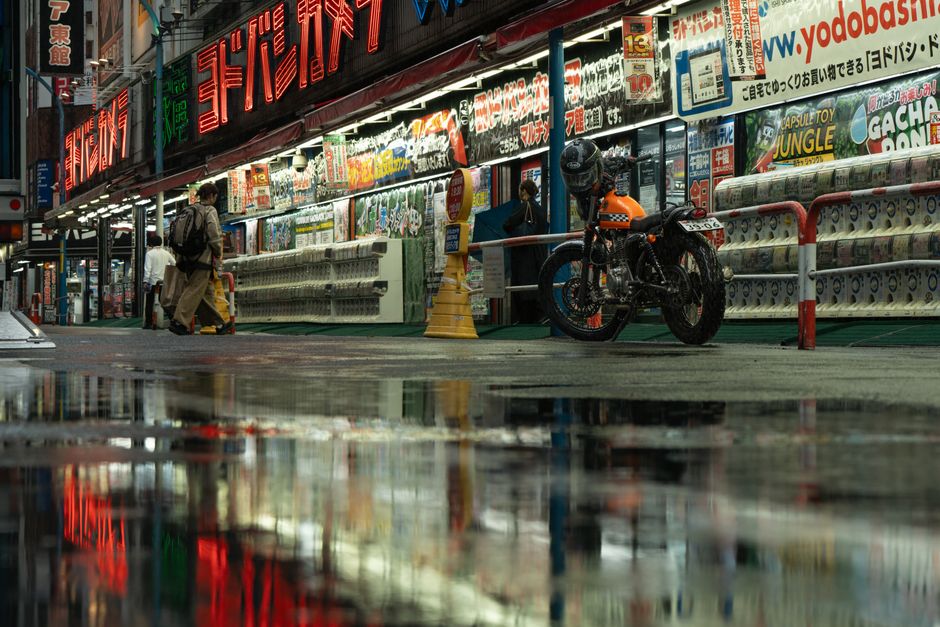 Japanese street at night with neon lights and rain reflections in Tokyo.