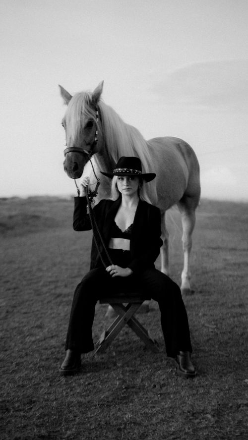 Free A stylish person in cowboy attire sits elegantly with a horse in a black and white portrait. Stock Photo
