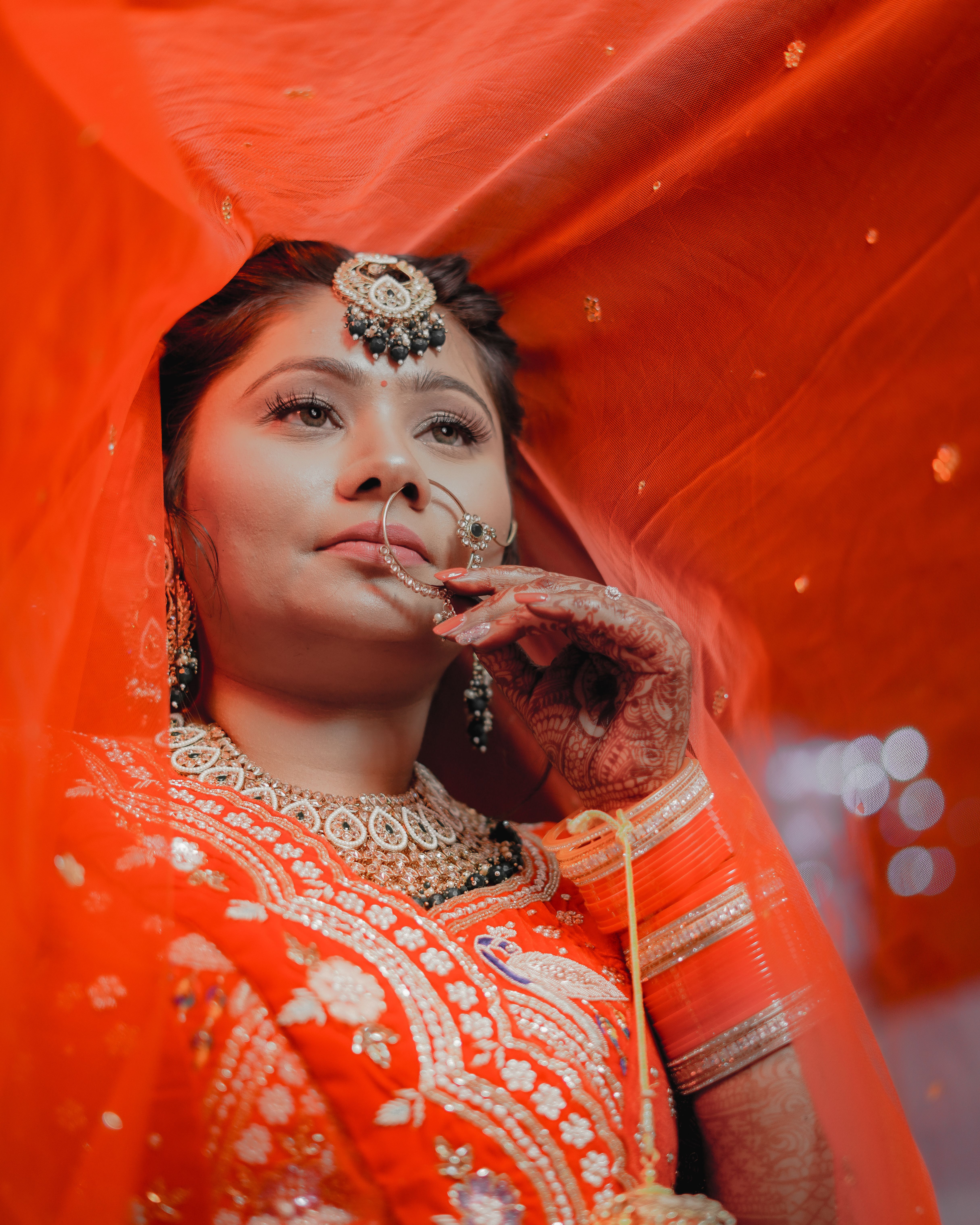 A beautiful Indian bride in traditional red attire with intricate jewelry and henna designs.