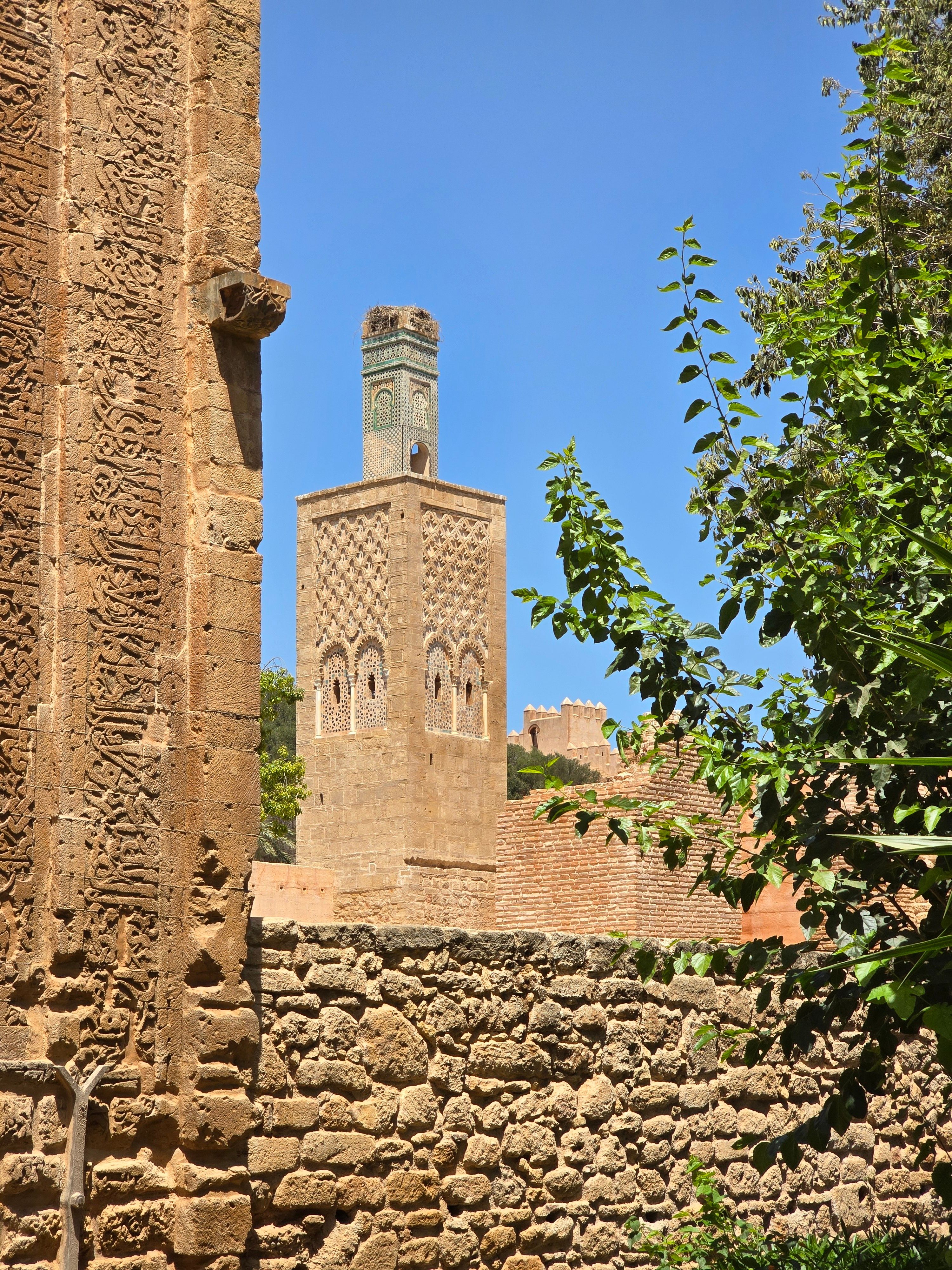 Explore the ancient architecture and intricate carvings of a Moroccan minaret under clear blue skies.